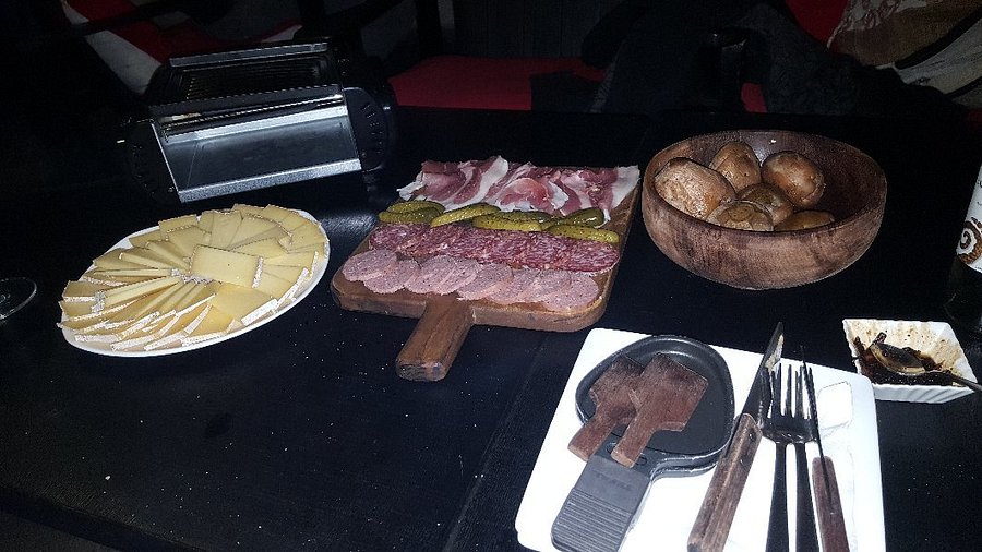 Traditional raclette with cheeses, charcuterie and potatoes